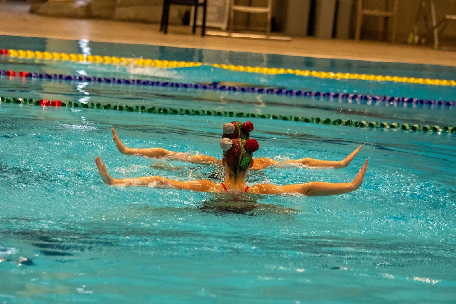 Two swimmers in matching caps performing a routine side by side.