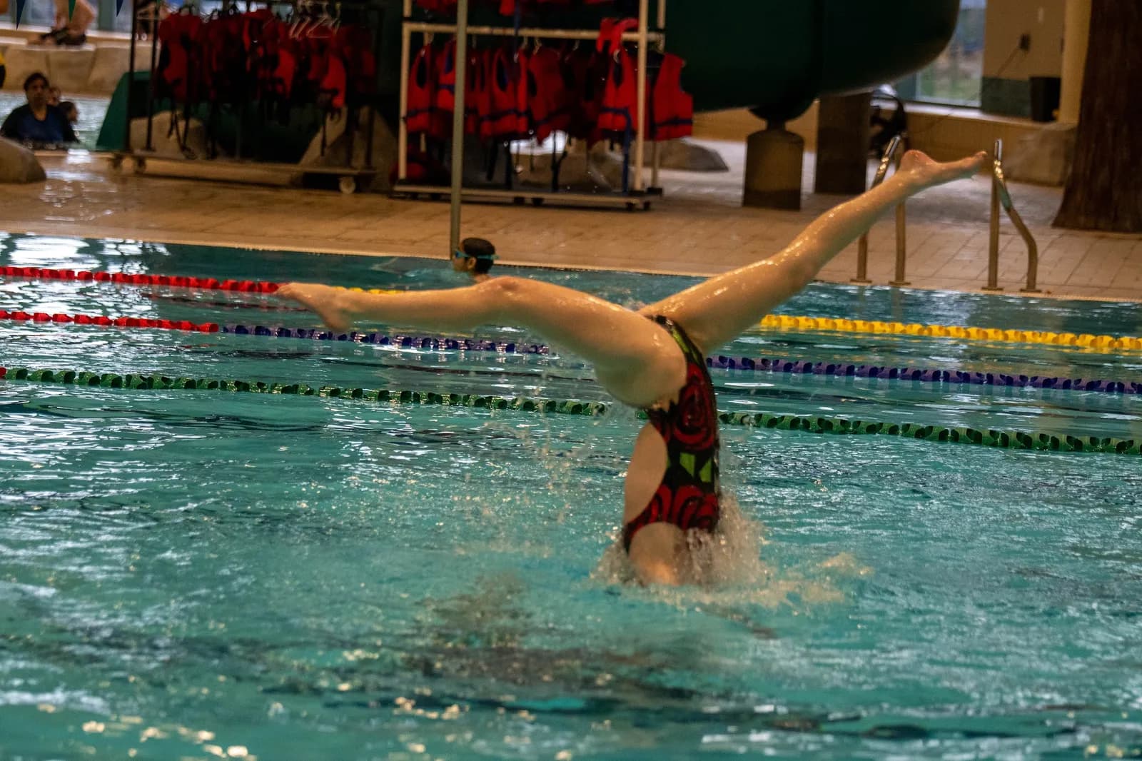 A swimmer holding a split above the water during a routine.